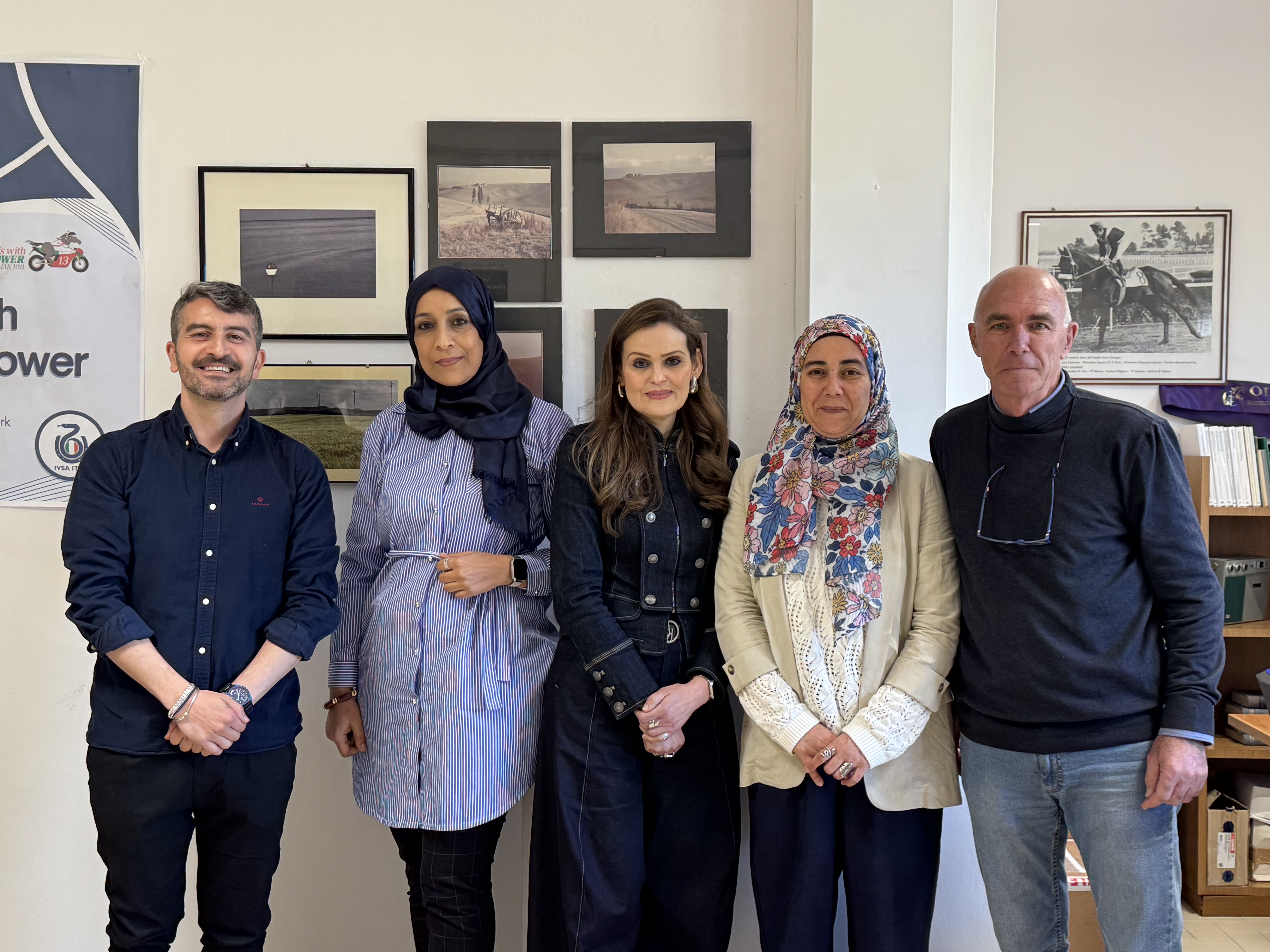Foto di gruppo in ambiente universitario al termine di un incontro accademico, con cinque partecipanti in posa