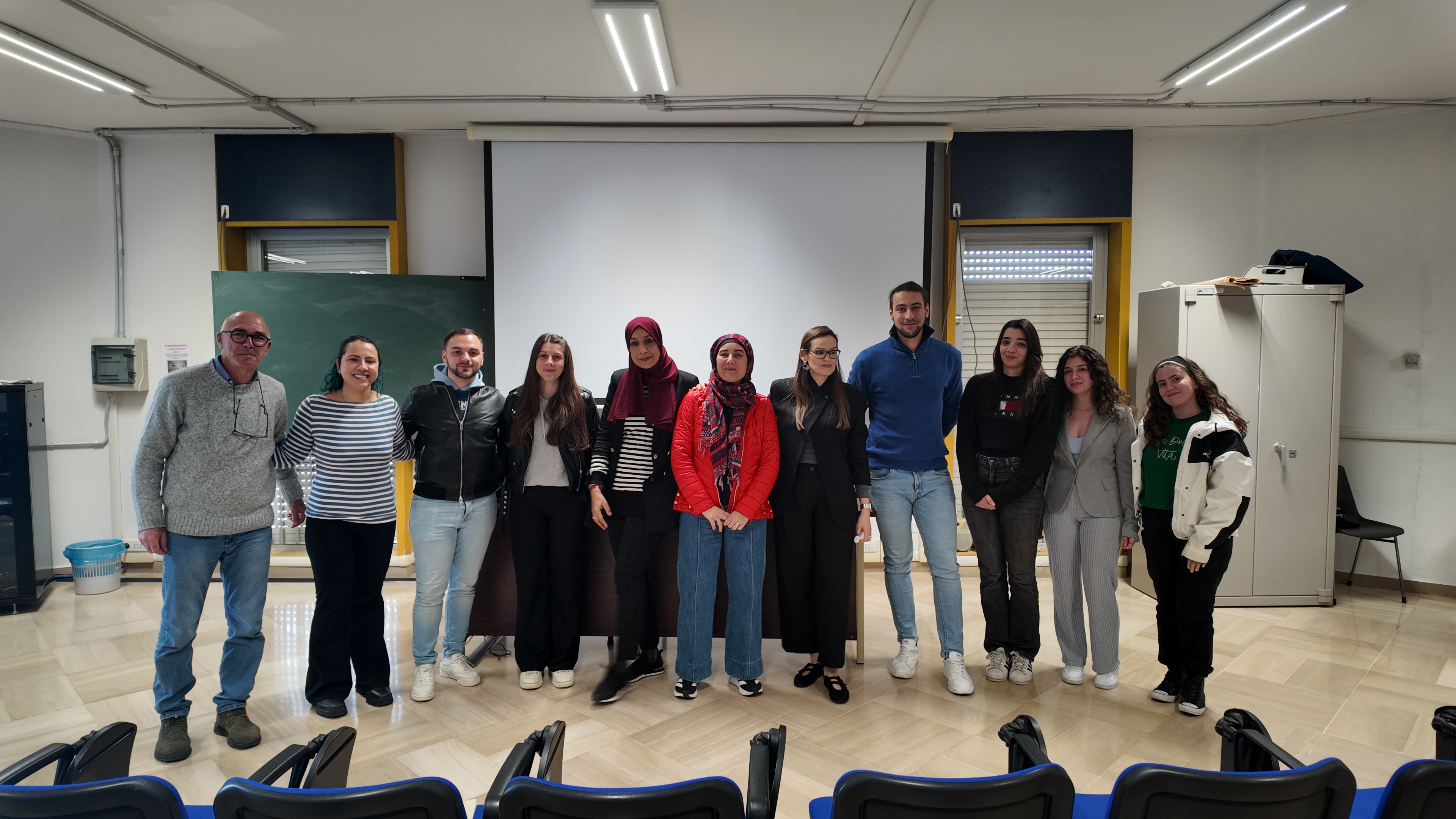 Foto di gruppo in aula universitaria con studenti e docenti al termine di una giornata di formazione o di un seminario scientifico.
