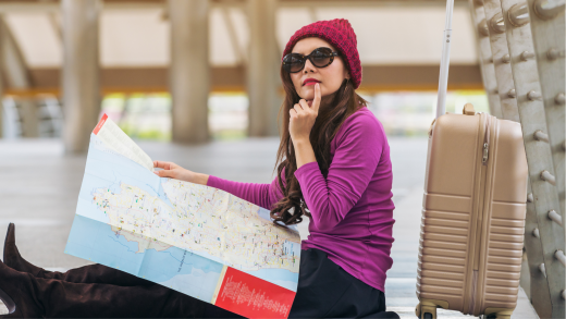 Ragazza seduta con una mappa e la valigia in procinto di partire